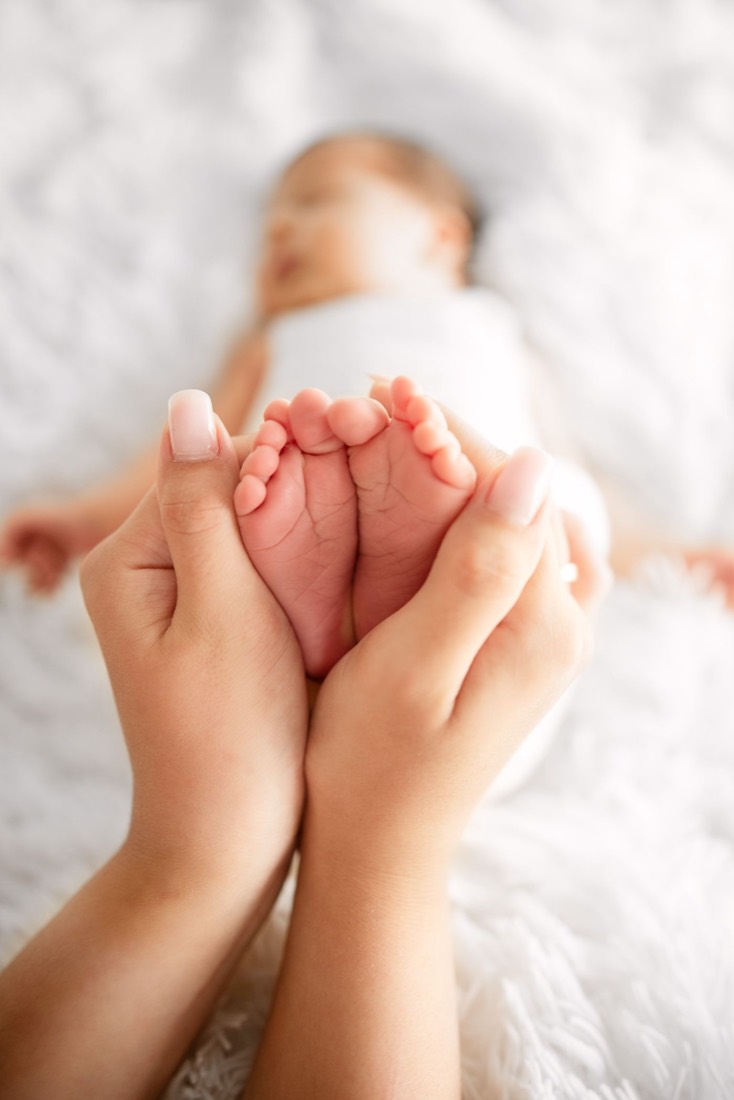 A newborn's feet held gently in a parent's hands